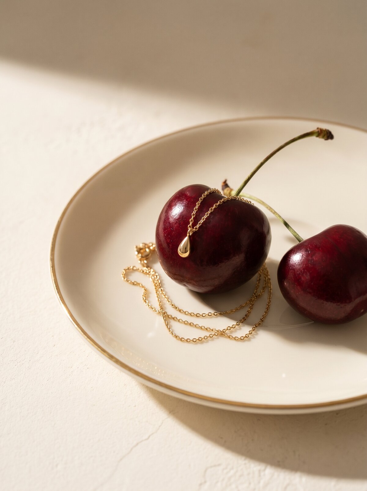 Everyday Luxury, necklace beside cherries on a plate